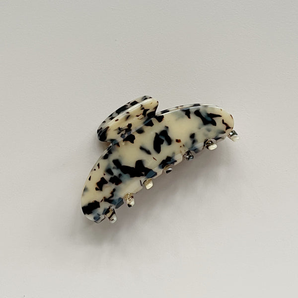 A large curved hair claw in a light tortoiseshell pattern against a neutral background.