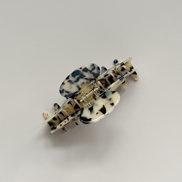 A top-down view of a light tortoiseshell patterned large hair claw against a neutral background.