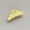 A pastel yellow cloud-shaped hair claw clip with the brand name 'kaxi' embossed on the top, shown on a neutral gray background.