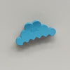 A light blue cloud-shaped hair claw clip with the brand name 'kaxi' embossed in the center, shown against a neutral light gray background.
