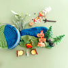 Toy play dough set with a blue mountain, trees, and small figures on a green background