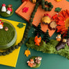 Playful autumn-themed playdough kit with toy animals, leaves, and a cake on a green surface.