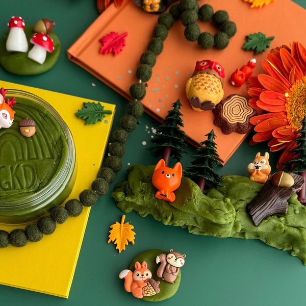 Playful autumn-themed playdough kit with toy animals, leaves, and a cake on a green surface.