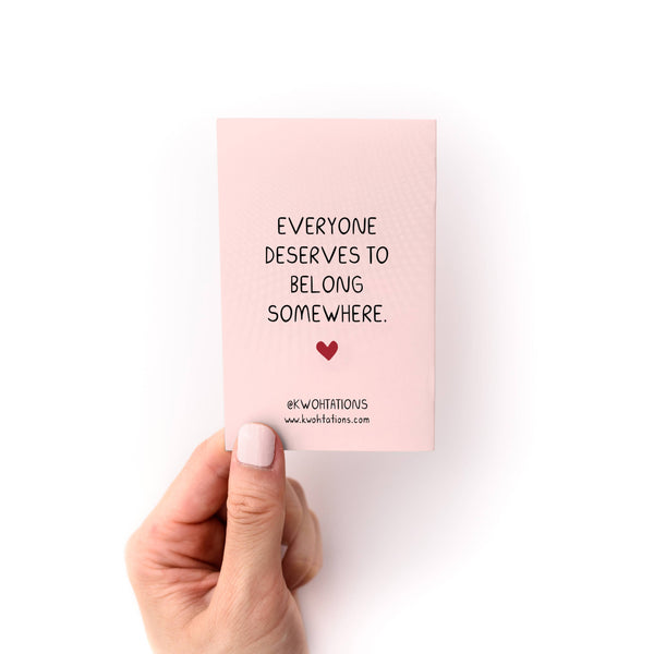Hand holding a pink zine with a motivational quote on a white background