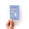 Blue mini zine back with space-themed design and text held by a hand on a white background