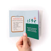 Hand holding a mini zine with a permission slip design on a white background