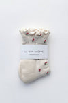 Pair of white socks with red floral patterns on a white background, labeled 'Le Bon Shoppe'.