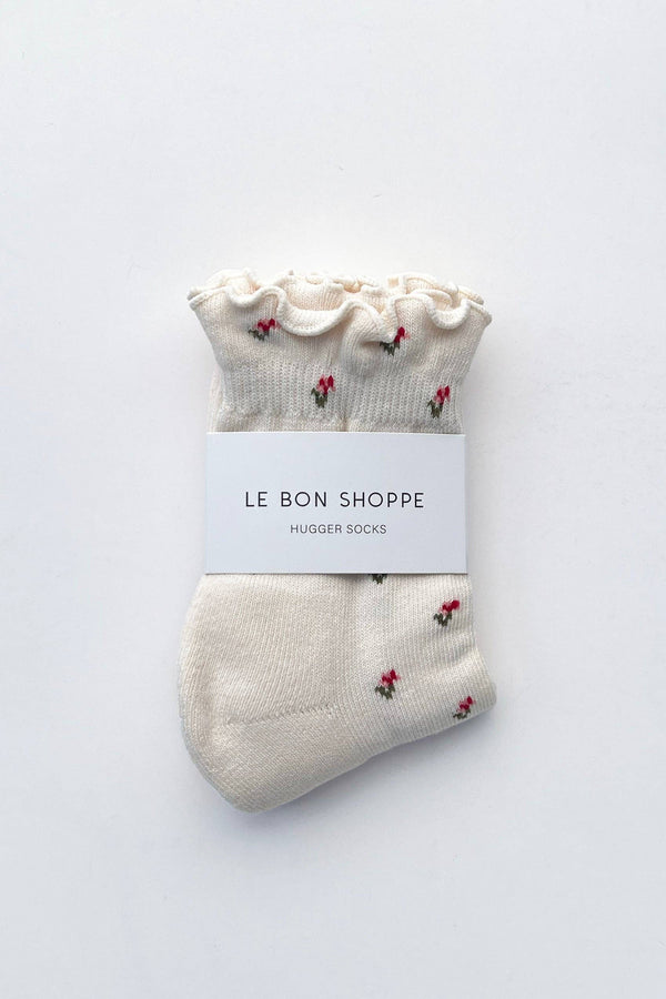 Pair of white socks with red floral patterns on a white background, labeled 'Le Bon Shoppe'.