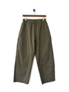 A pair of army green cotton-nylon elastic waist pants on a wood hanger against a white wall. 