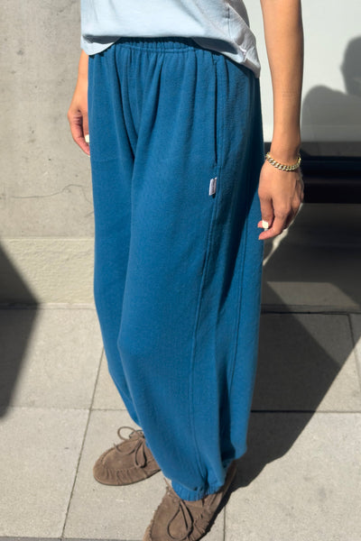 Person wearing teal blue pants and a light shirt on a concrete surface
