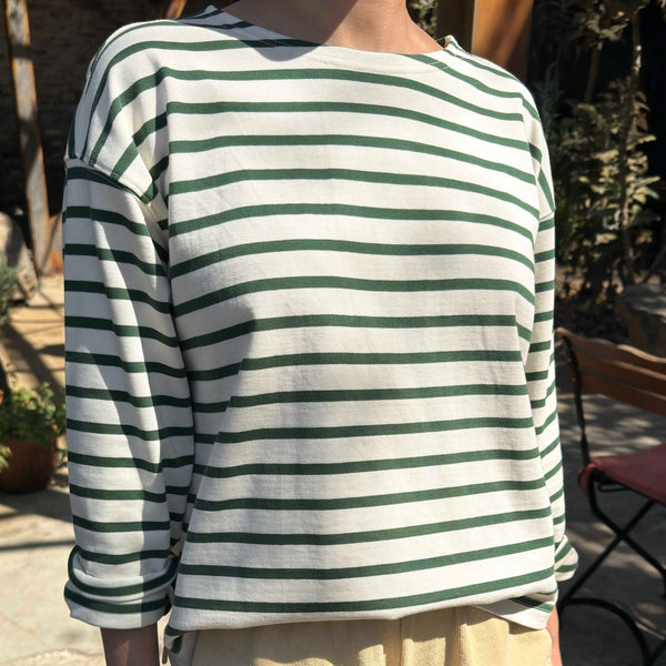 Person wearing a green and white striped shirt with beige shorts outdoors.