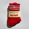 Red sock with white stripes and a silver embroidered heart with 'Lebon Shoppe' label on a light gray background