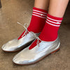 Silver shoes with red socks on a brown floor