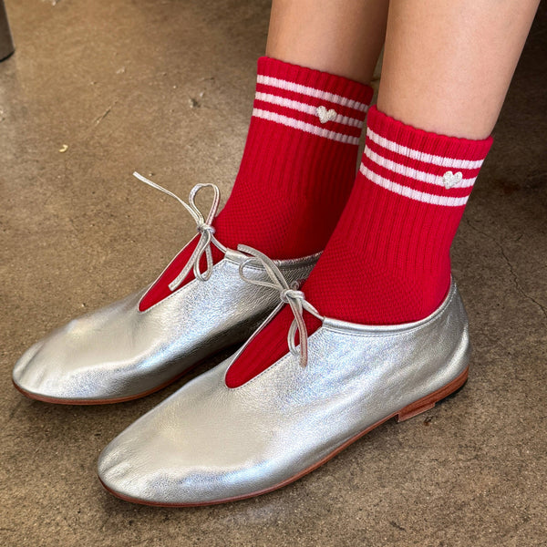 Silver shoes with red socks on a brown floor