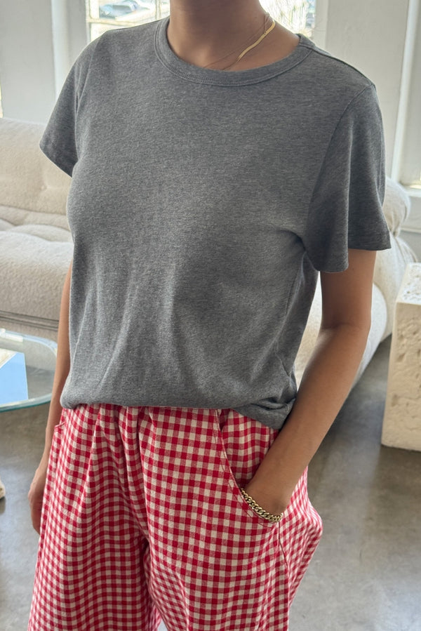 Person wearing a gray t-shirt and red checkered pants in a living room.