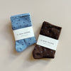 Two pairs of polka dot fine knit socks in light blue & navy, and brown & light blue, against a neutral backdrop.
