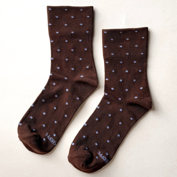 A pair of brown and light blue polka dot sneaker socks on a neutral background.