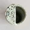 A top-down view of a ceramic travel mug featuring an off-white and brown speckled glaze.