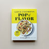 A cookbook in bright yellow and white with a photo of a pasta entree. The book is called 'Love & Lemons Pop of Flavor' by Jeanine Donofrio. The book sits against a neutral backdrop.