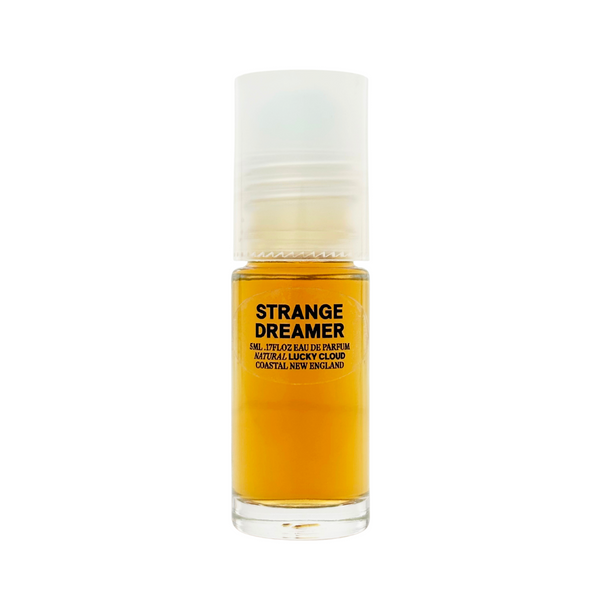 A small clear roll-on bottle of amber colored natural perfume by Lucky Cloud called 'Strange Dreamer' against a white background.