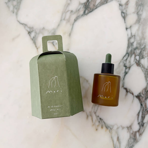 Brown bottle of body oil with dropper and green box on a marble surface