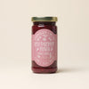 Jar of raspberry-tangerine fruit spread with a pink label on a beige background