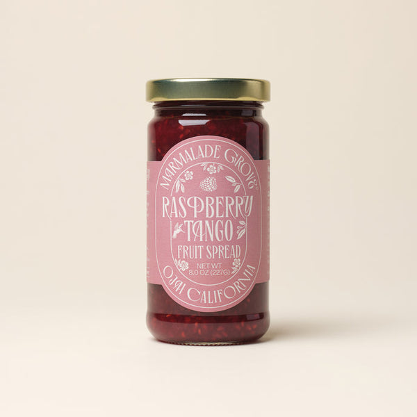 Jar of raspberry-tangerine fruit spread with a pink label on a beige background