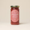 A glass jar of Strawberry Meyer Lemon fruit spread with a pink label on a neutral background.