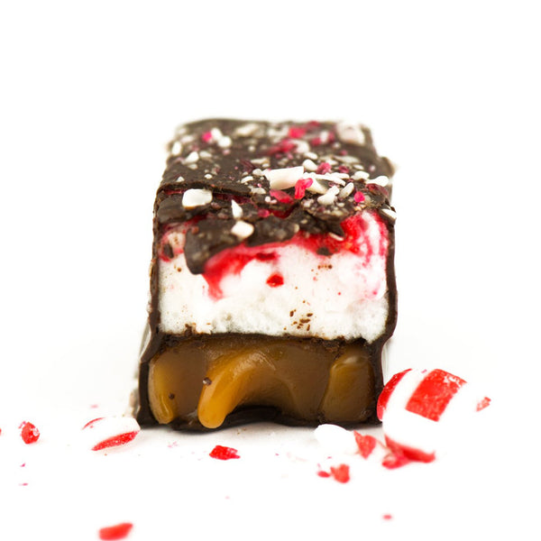 Chocolate-covered treat with marshmallow, caramel, and crushed candy cane on a white background