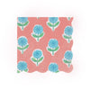 Wavy-edged paper napkin featuring a pattern of blue flowers with green stems on a pink background