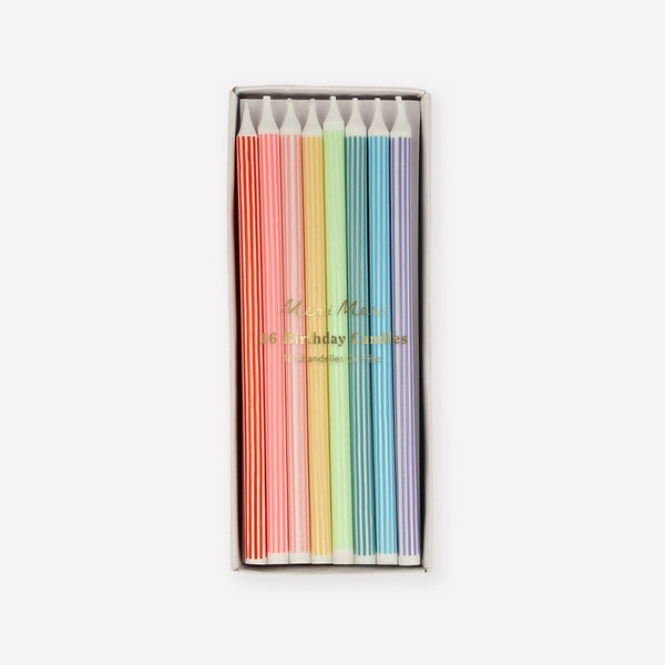 Box of long colorful striped birthday candles on a white background