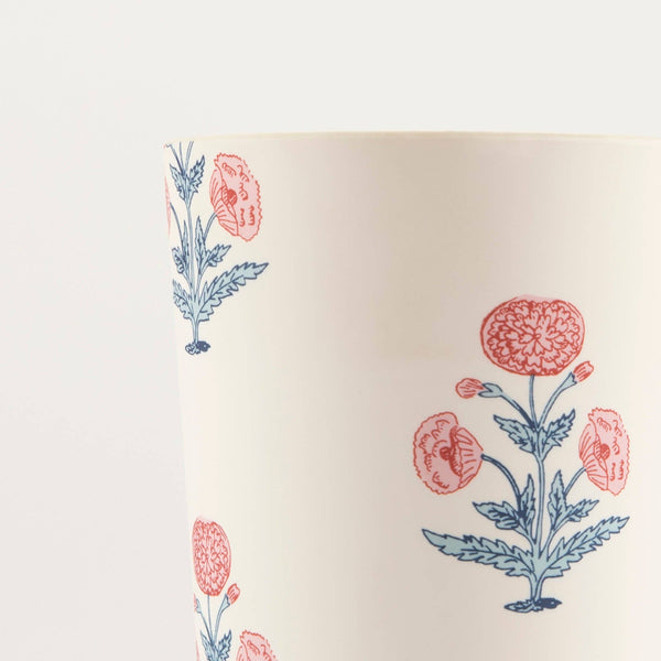 Close up detail of a melamine cup printed with a pink and blue floral design on a white background