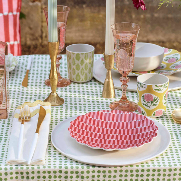Decorative table setting with pink and gold glassware, checkered plates, and floral-patterned cups on a polka dot tablecloth.