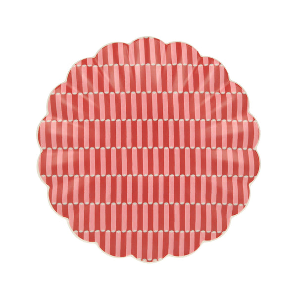 Round red and pink patterned small plate with a wavy edge on a white background