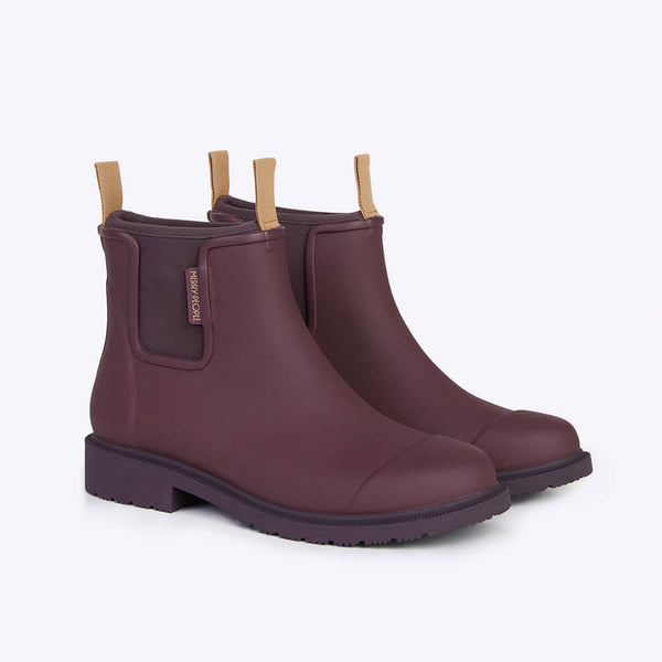 A pair of dark cherry red ankle height rain boots with tan pull tabs and black soles against a white backdrop.