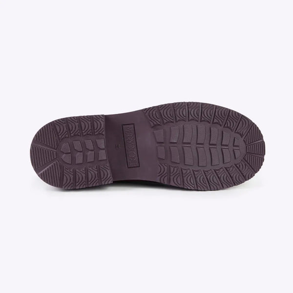 A view of the bottom tread soles of a rainboot on a white backdrop.
