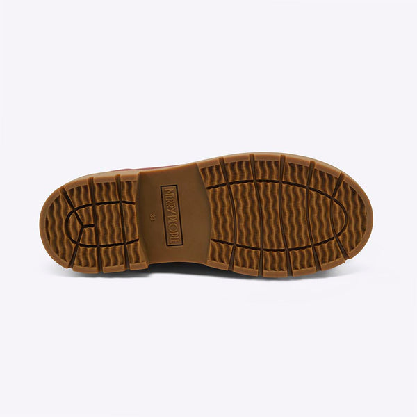 A bottom view of a treaded sole of a boot against a white backdrop.