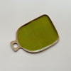 A ceramic serving tray with a circular handle and a bright olive green speckled glaze in an oblong shape against a neutral backdrop.