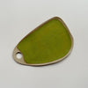 A ceramic serving tray with a circular handle and a bright olive green speckled glaze in an oblong wedge shape against a neutral backdrop.