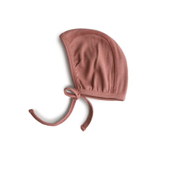 Pinkish-red ribbed baby bonnet on a white background