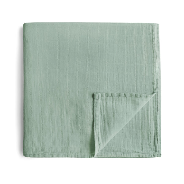 A green muslin cotton baby swaddle blanket folded on a white background.