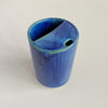 Top-down view of a small ceramic to-go cup featuring a vibrant blue glaze with subtle pops of green photographed against a neutral backdrop.