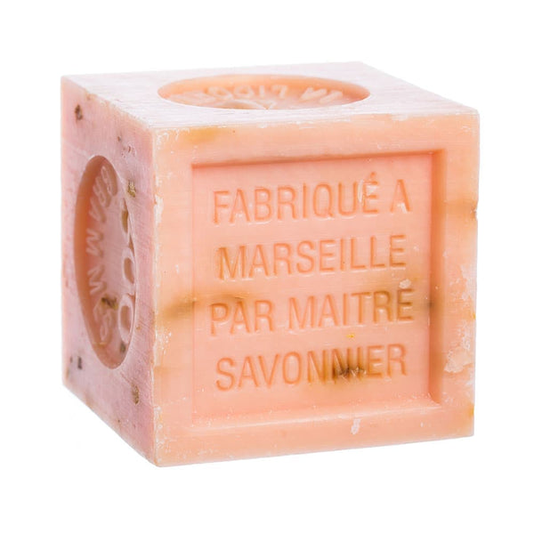 Orange scented orange-pink square cube of soap with text on a white background