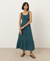 Woman wearing a teal dress standing against a white background