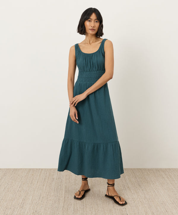 Woman wearing a teal dress standing against a white background