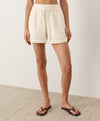 Person wearing cream shorts on a neutral background