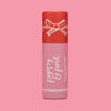 A single lip balm tube standing upright on a solid pink background. The tube is red on top with a white bow illustration and pink on the lower half, featuring the text 'poppy & pout' and 'Candy Cane Fluff' in white script.