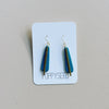 Blue clay and brass earrings on a Poppy Seed branded card against a gray background