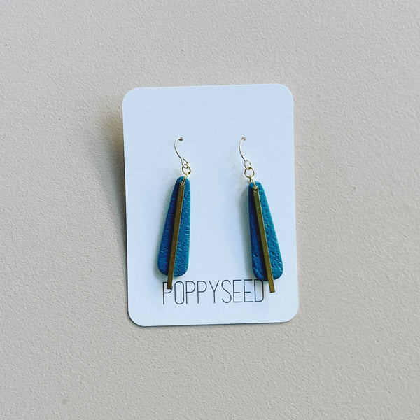 Blue clay and brass earrings on a Poppy Seed branded card against a gray background