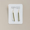 White clay and brass long teardrop earrings on a Poppyseed branded card against a beige background